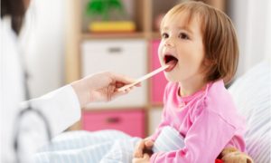 The doctor examines the baby's tongue.
